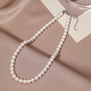 Detail of elegant cream pearl necklace with polished silver-tone clasp on silk