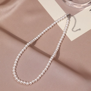 Detail of elegant white pearl necklace with silver lobster clasp on silk fabric
