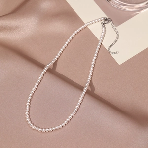 Detail of elegant pearl necklace with silver lobster clasp on champagne satin background