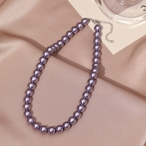 Detailed view of elegant purple pearl necklace with silver lobster clasp on silk fabric