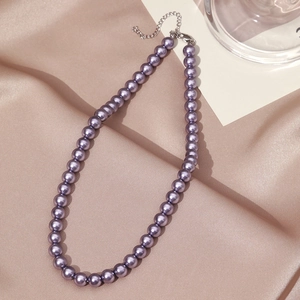 Close-up of purple pearl necklace with silver lobster clasp on champagne silk background