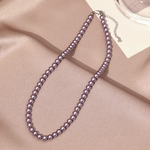 Macro detail of purple pearl necklace with adjustable silver chain on satin fabric
