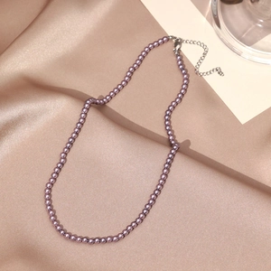Detail of lavender pearl necklace with adjustable metal clasp on silk background