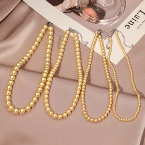 Detail of four champagne pearl necklaces with lobster clasps on elegant silk fabric