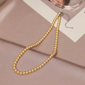 Close-up of golden pearl necklace with silver lobster clasp and adjustable tail chain