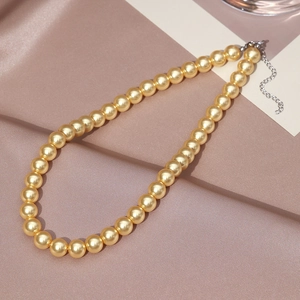 Detail of elegant gold pearl necklace with adjustable lobster clasp on silk background