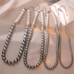 Elegant multi-size gradient pearl necklaces with silver clasp on silk background