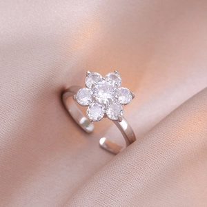 Elegant floral silver open ring with sparkling zircon petals on soft silk background