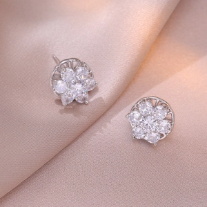 Silver flower stud earrings with sparkling zircon petals on soft silk fabric
