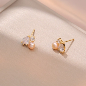 Elegant gold freshwater pearl earrings with sparkling zircon stones on champagne silk