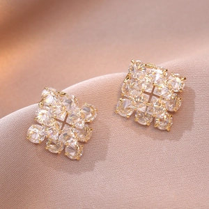 Boucles d'oreilles carrées en zircone dorée sur fond de soie couleur champagne