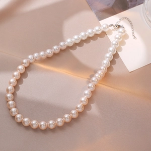Collier de perles dégradé rose et blanc élégant avec fermoir argenté sur tissu texturé