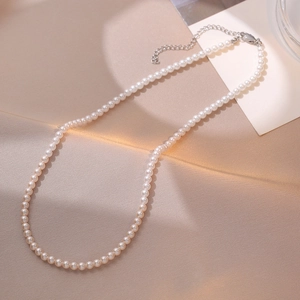 Collier de perles élégant avec dégradé rose et blanc sur un tissu beige texturé