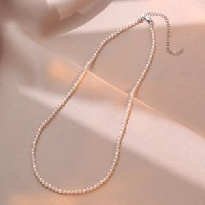 Detail view of dainty 3-4mm pearl necklace with adjustable heart charm extension chain