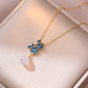Vintage gold necklace with blue enamel flower and white agate pearl pendant on a box