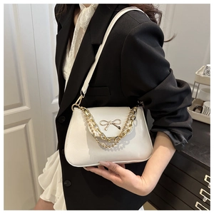 Close-up of stylish white PU leather shoulder bag featuring a gold metal bow and chain detail