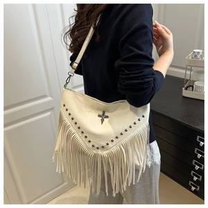 Detail of cream tassel shoulder bag with studs and black metal cross decoration