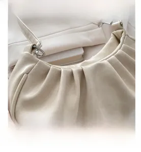 Detail of ruched cream PU leather shoulder bag featuring silver metal rings and pleats