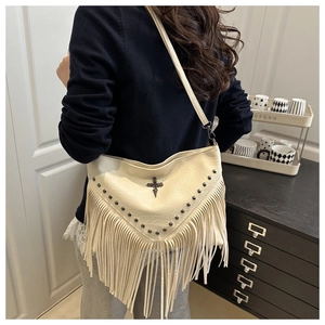 Detail view of off-white hobo bag with vintage metal studs and long tassel accents