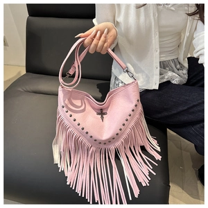 Detailed shot of pink leather crossbody bag with metal studs and long fringe tassels