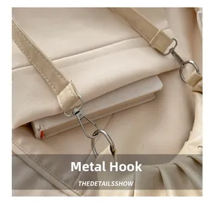 Detail of silver hardware hook and pleated beige leather on a minimalist shoulder bag