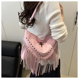 Detail of pink tassel bag with metallic rivets and a vintage cross pendant charm