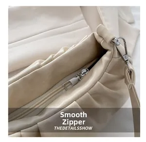 Detail showing smooth silver metal zipper and soft cream pleated leather texture