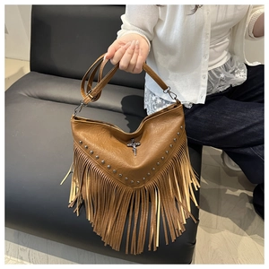 Close-up of brown PU leather shoulder bag with metallic rivets, cross charm, and long tassels