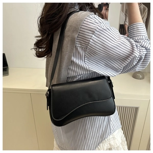 Chic black leather crossbody bag with asymmetric wavy flap design shown on model