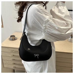 Close-up of black hobo shoulder bag featuring a delicate silver metal bow detail
