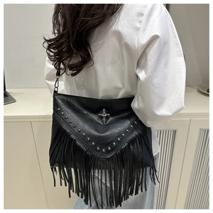 Detail of black faux leather crossbody bag with tassels and metallic rivet studs