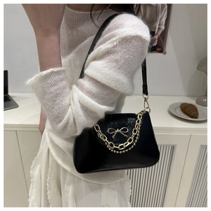 Detail of black PU leather shoulder bag featuring a gold bow buckle and thick chain strap