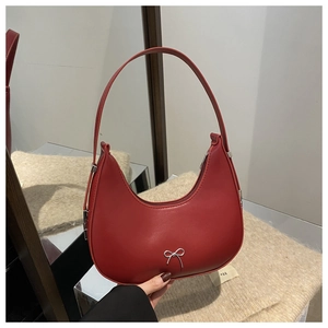 Detail of red leather hobo bag featuring a decorative silver metal bow and zipper closure