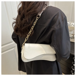 Detailed view of a white saddle-style underarm bag with a bold gold chain strap