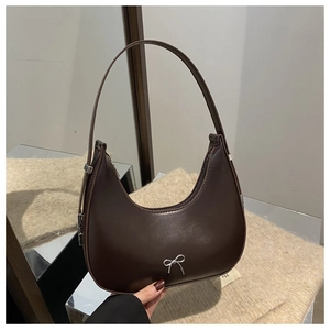 Detail of silver bow metallic ornament on dark brown PU leather hobo bag