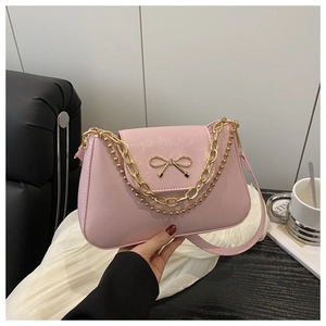 Pink faux leather shoulder bag featuring a metallic bow detail and golden chain straps