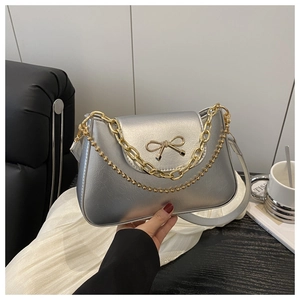 Detailed shot of silver metallic shoulder bag with gold bow clasp and stylish double chains