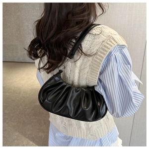 Close-up of black pleated crescent shoulder bag with silver hardware on a model