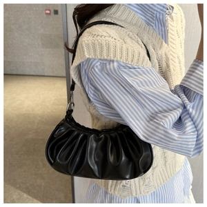 Détail d'un sac demi-lune noir plissé en similicuir avec une texture lisse