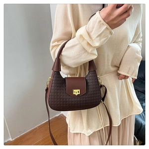 Detail of dark brown woven texture handbag with golden metal buckle and adjustable strap