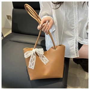 Primer plano de bolso marrón con lazo de encaje blanco y letras doradas de moda