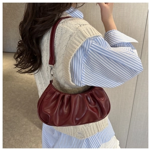Détail du sac hobo bordeaux froncé avec plis verticaux et boucles métalliques argentées