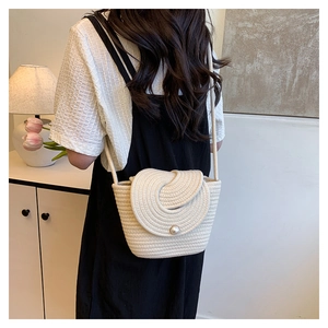 Detail of cotton rope woven crossbody bag with pearl closure and spiral flap design