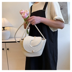 Détail d'un sac tissé crème avec un rabat en spirale et un fermoir en perle élégant