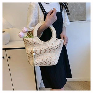Détail du sac seau en paille tissé main avec pois marrons, pompon et poignée ronde