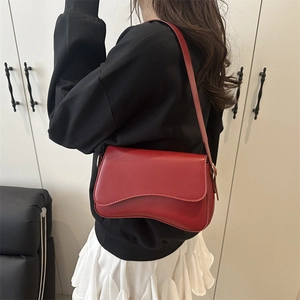 Stylish red saddle bag with wave-curve flap on a model wearing black hoodie