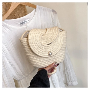 Détail du sac à bandoulière tissé beige avec fermoir magnétique décoratif en perle