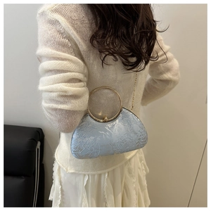 Light blue floral embroidered evening bag with gold ring handles on a white outfit