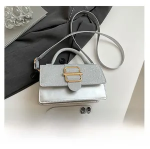 Silberne Handtasche mit Glitzerpanel und Schnalle neben Smartphone zum Größenvergleich