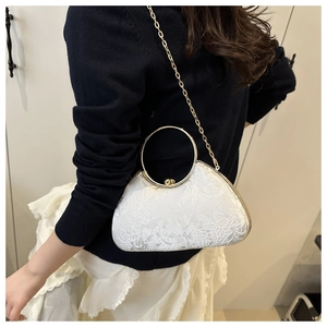 Detail der bestickten beigen Abendtasche mit goldenem Griff und Kettenriemen